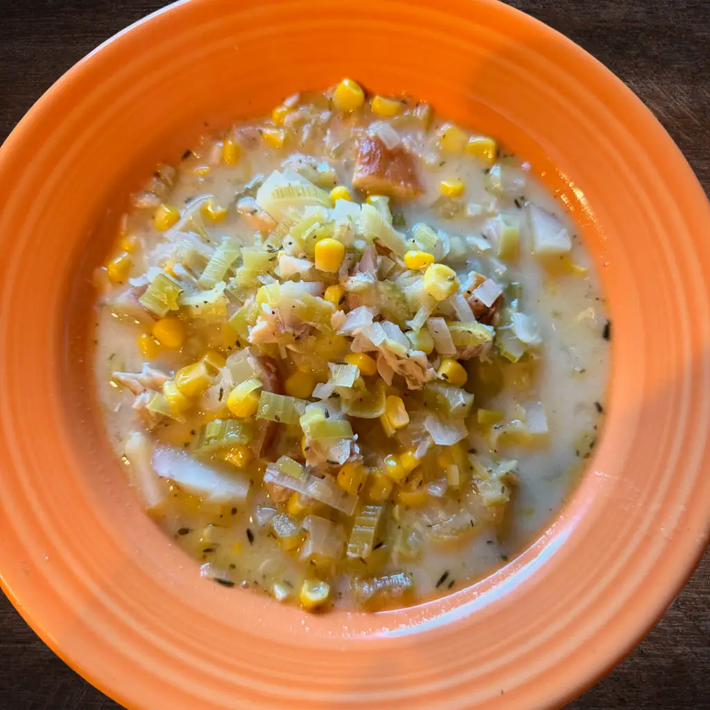 Smoked trout chowder with corn, potatoes, celery, and fresh herbs in a light cream broth