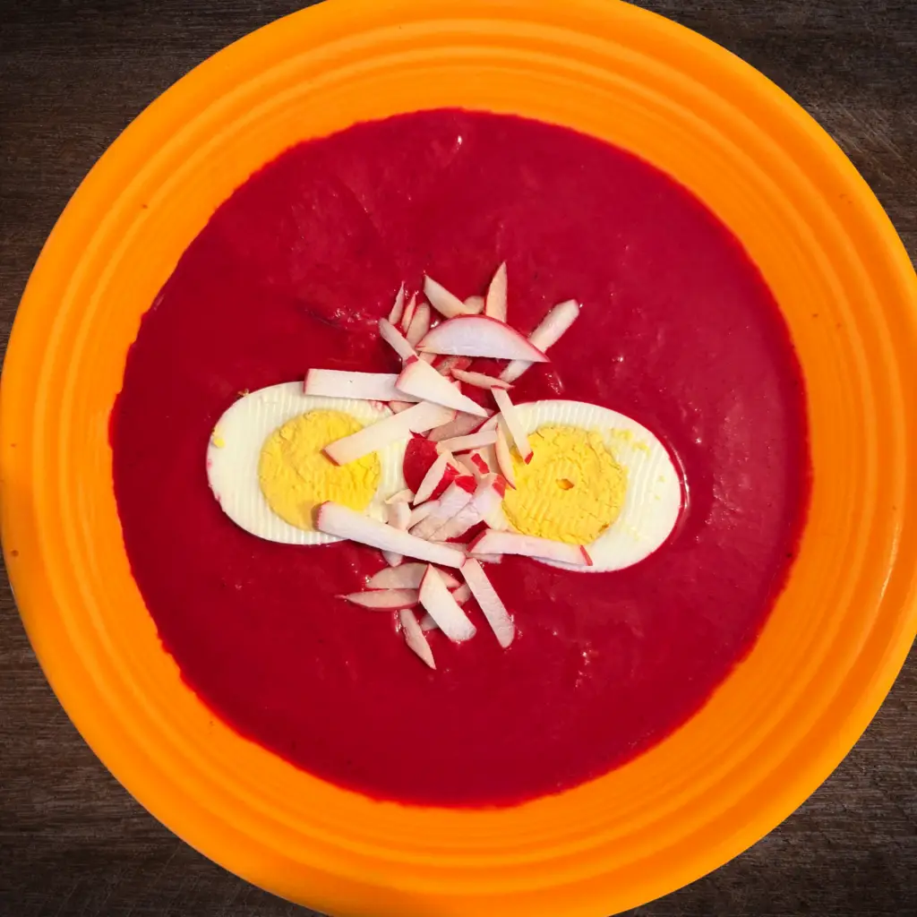 Bright beet borscht topped with hard-boiled egg and fresh sliced radish